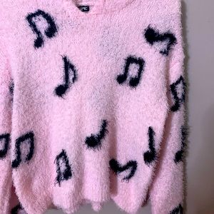 Pink fuzzy sweater with black music notes